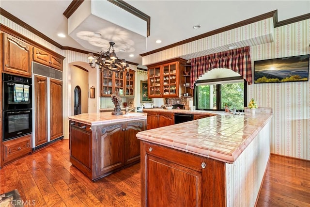 kitchen with a notable chandelier, crown molding, black appliances, and a center island