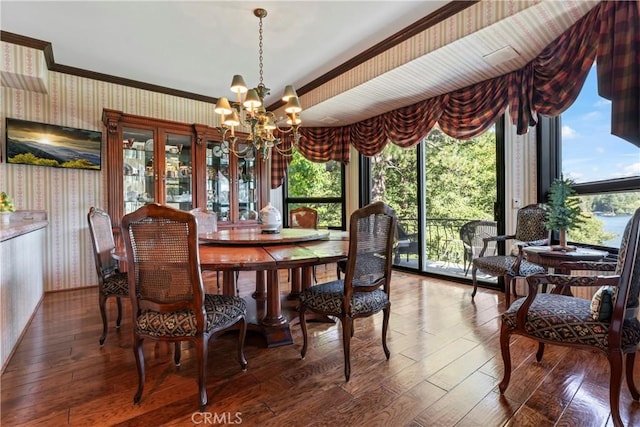 dining area with crown molding, hardwood / wood-style flooring, and a notable chandelier