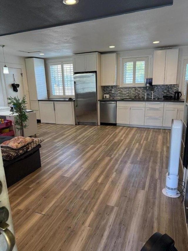 kitchen with wood-type flooring, white cabinetry, appliances with stainless steel finishes, and a wealth of natural light