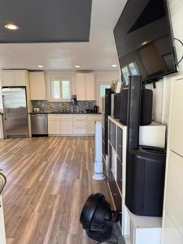 kitchen featuring white cabinetry, backsplash, appliances with stainless steel finishes, and light hardwood / wood-style flooring