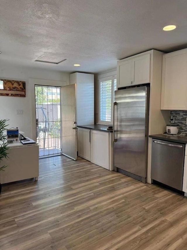 kitchen featuring wood-type flooring, white cabinets, and stainless steel appliances