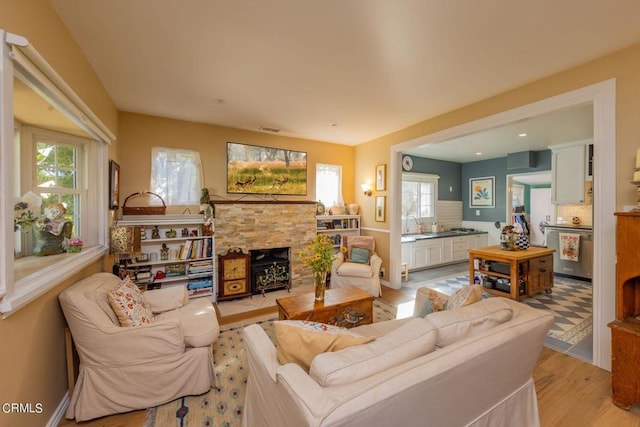 living room with a healthy amount of sunlight, a fireplace, sink, and light hardwood / wood-style floors