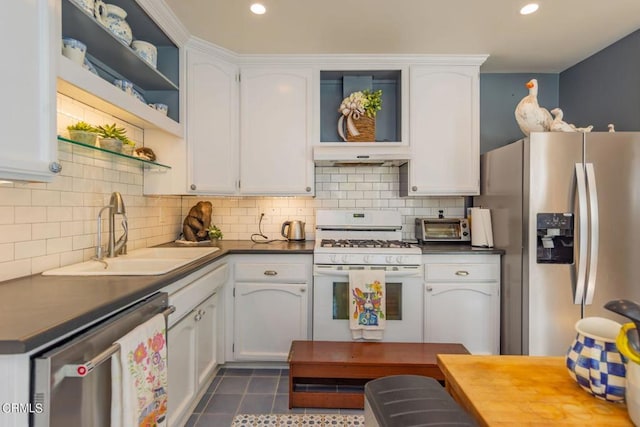 kitchen with dark tile patterned floors, stainless steel appliances, white cabinets, and sink