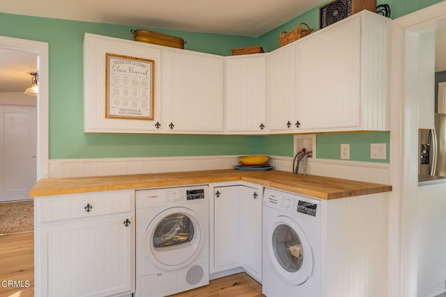 laundry room featuring washer and dryer, cabinets, and light wood-type flooring