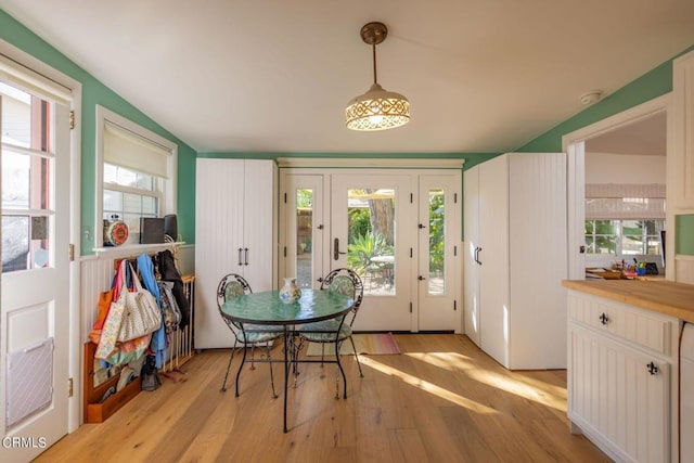 dining room with light wood-type flooring and vaulted ceiling