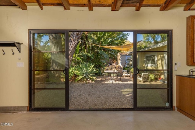 doorway to outside featuring concrete flooring and beam ceiling