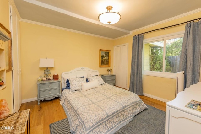 bedroom with light wood-style floors, crown molding, and baseboards