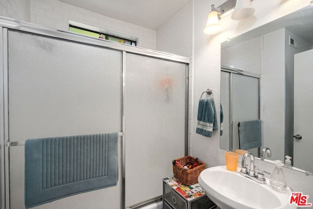 bathroom with sink and a shower with shower door