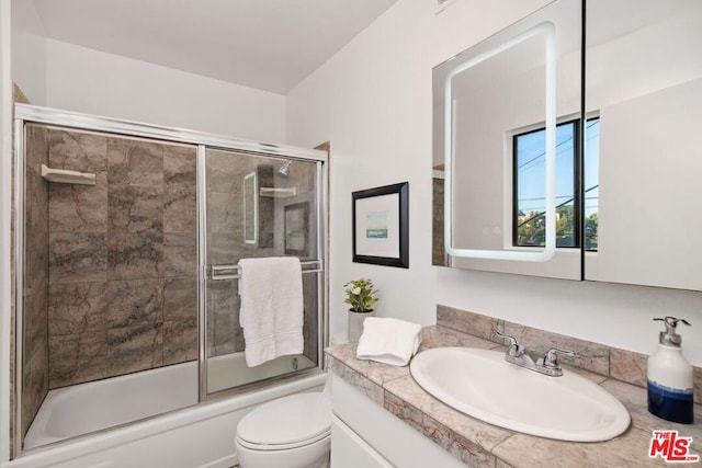 full bathroom featuring vanity, bath / shower combo with glass door, and toilet