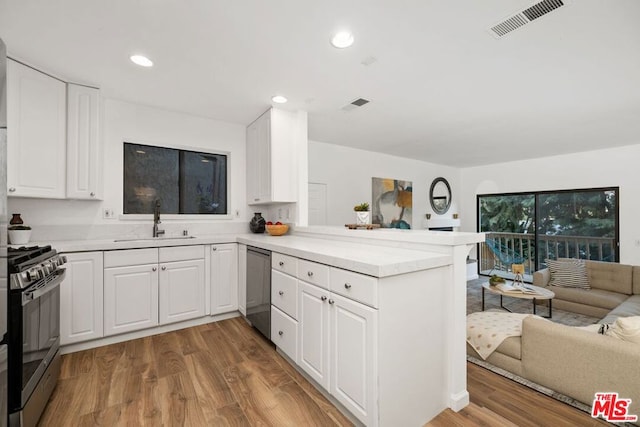 kitchen featuring sink, stainless steel appliances, kitchen peninsula, white cabinets, and hardwood / wood-style flooring