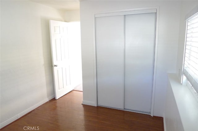 unfurnished bedroom featuring dark hardwood / wood-style flooring and a closet