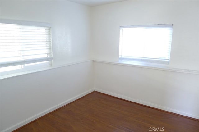 unfurnished room featuring a wealth of natural light and dark hardwood / wood-style floors