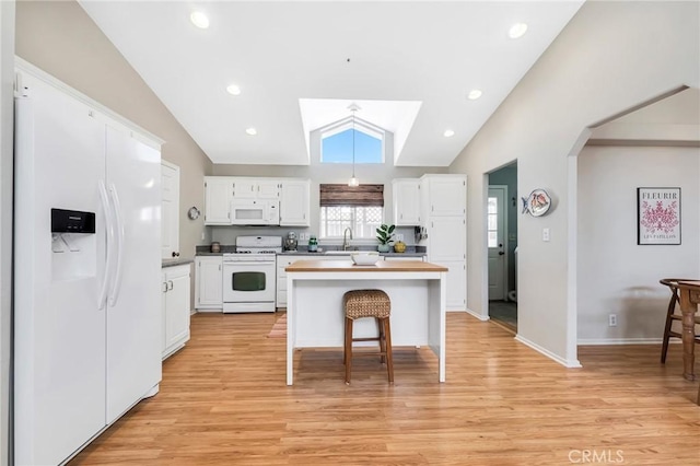 kitchen with vaulted ceiling, white appliances, white cabinetry, and a sink