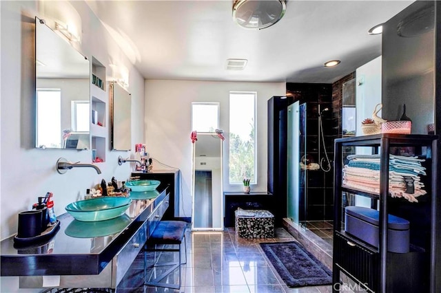 bathroom with a shower, vanity, and a healthy amount of sunlight