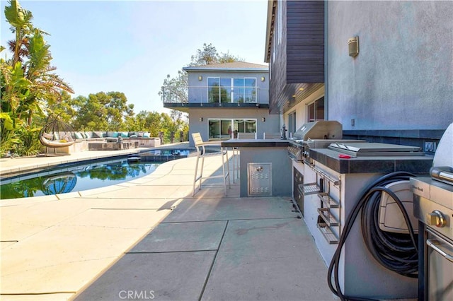 view of swimming pool featuring a grill, a patio area, and exterior kitchen