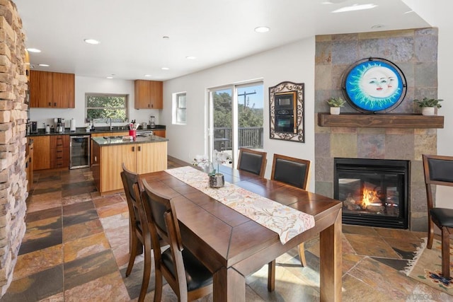 dining space with beverage cooler, a wealth of natural light, sink, and a large fireplace