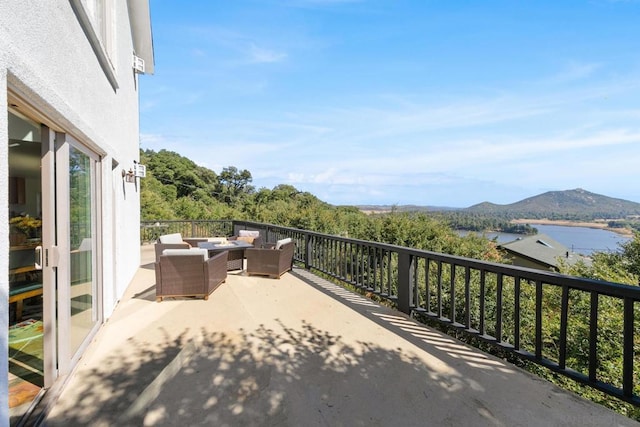 view of patio / terrace with a water and mountain view, a balcony, and an outdoor hangout area