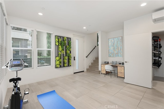 exercise room featuring a wall mounted AC and light tile patterned floors