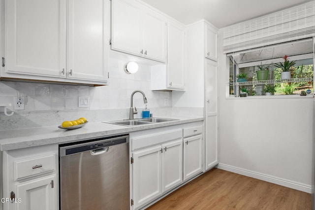 kitchen featuring decorative backsplash, white cabinetry, light wood-type flooring, stainless steel dishwasher, and sink