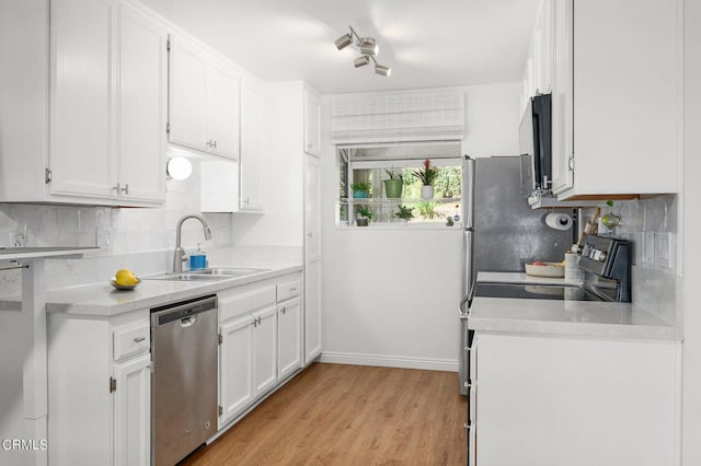 kitchen with tasteful backsplash, white cabinets, stainless steel appliances, light hardwood / wood-style flooring, and sink