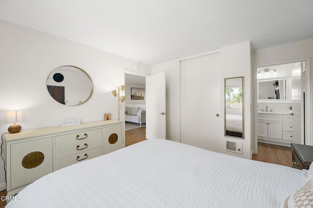 bedroom featuring sink, a closet, connected bathroom, and dark hardwood / wood-style flooring