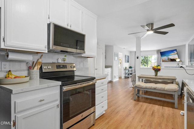 kitchen featuring white cabinets, light hardwood / wood-style flooring, stainless steel appliances, decorative backsplash, and ceiling fan