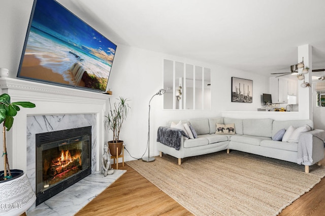 living room featuring ceiling fan, a high end fireplace, and hardwood / wood-style flooring