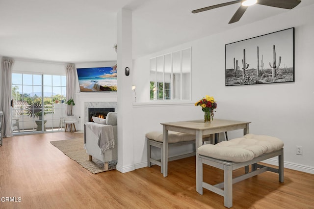 dining space featuring ceiling fan, light hardwood / wood-style floors, and a fireplace