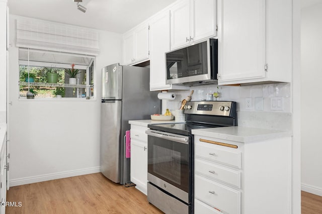 kitchen featuring backsplash, white cabinetry, light hardwood / wood-style flooring, and stainless steel appliances