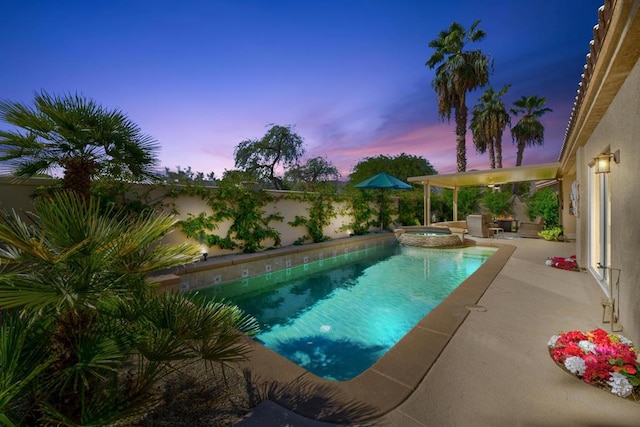 pool at dusk with a patio area and an in ground hot tub