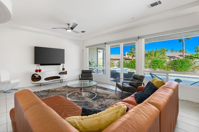 living room with a wealth of natural light, ceiling fan, light tile patterned flooring, and crown molding