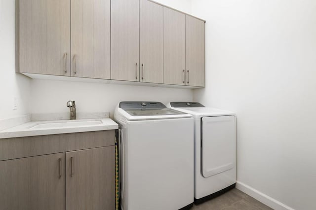 washroom with cabinets, washing machine and clothes dryer, light tile patterned flooring, and sink