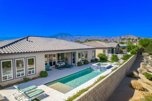 back of house with a swimming pool with hot tub, a mountain view, and a patio area