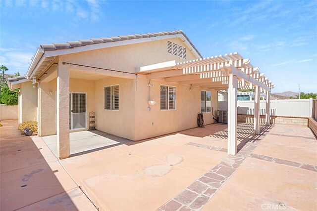 rear view of property featuring a pergola and a patio area