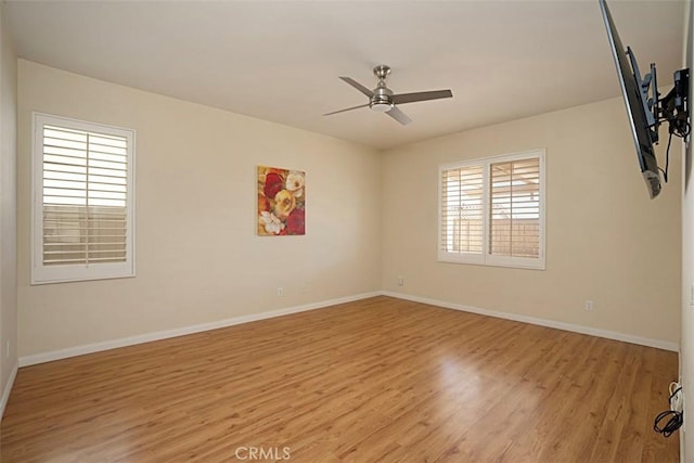 spare room featuring ceiling fan, a healthy amount of sunlight, and light wood-type flooring