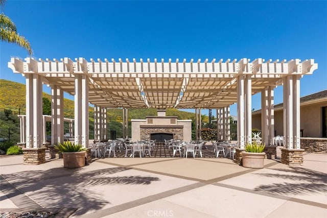 view of patio / terrace featuring a pergola and an outdoor stone fireplace