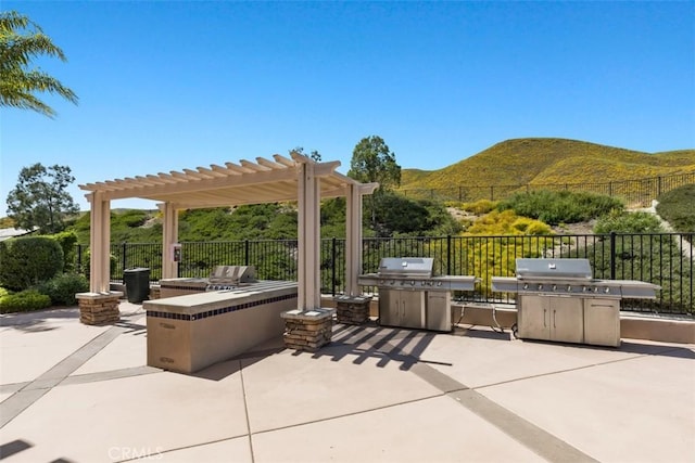 view of patio featuring a mountain view, an outdoor kitchen, grilling area, and a pergola