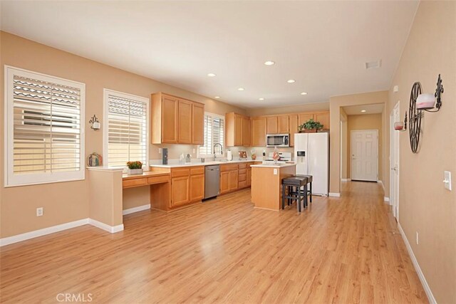 kitchen with a kitchen bar, a center island, stainless steel appliances, and light hardwood / wood-style flooring