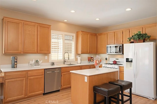 kitchen with light wood-type flooring, stainless steel appliances, sink, a center island, and a breakfast bar area