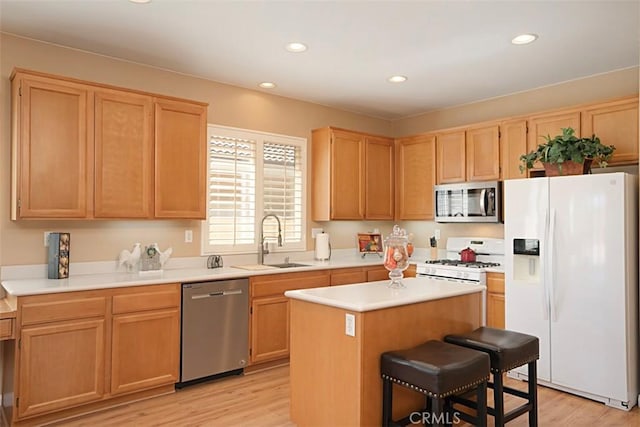 kitchen featuring sink, a kitchen island, stainless steel appliances, a kitchen bar, and light wood-type flooring