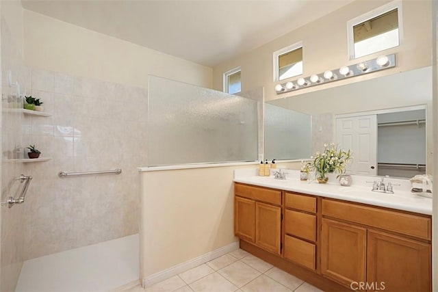 bathroom featuring tile patterned flooring, a tile shower, and vanity