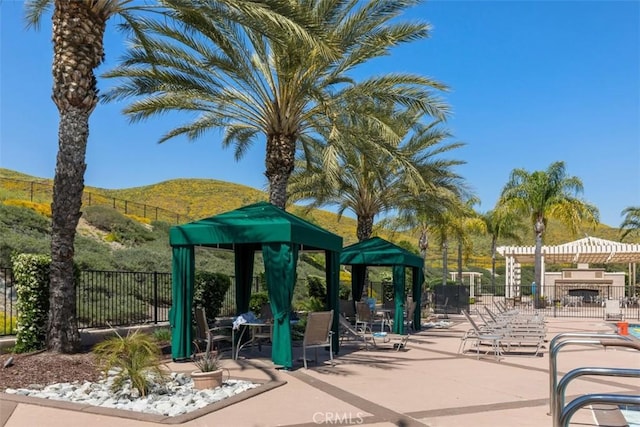 view of community with a pergola, a mountain view, and a patio