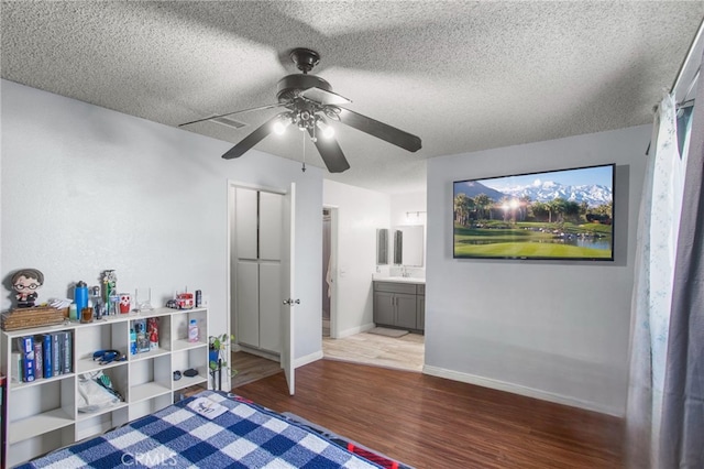 bedroom with ceiling fan, ensuite bathroom, hardwood / wood-style floors, and a textured ceiling