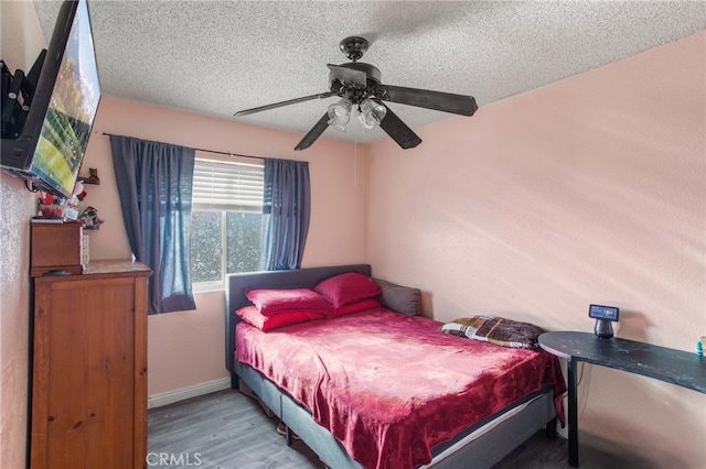 bedroom with ceiling fan, a textured ceiling, and hardwood / wood-style floors