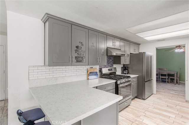 kitchen with light hardwood / wood-style floors, kitchen peninsula, gray cabinets, stainless steel appliances, and ceiling fan