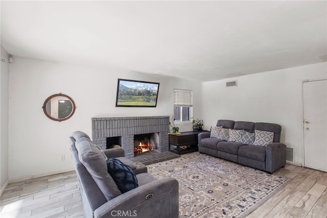 living room featuring light hardwood / wood-style floors and a brick fireplace