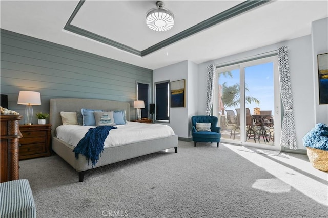 bedroom featuring a tray ceiling, carpet, and wood walls