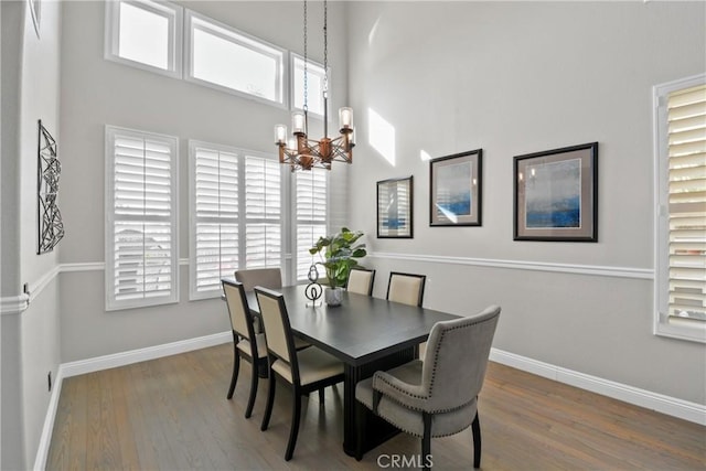 dining area with a high ceiling, dark hardwood / wood-style floors, and a chandelier