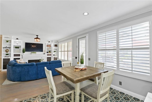 dining area featuring built in shelves, ornamental molding, and hardwood / wood-style flooring