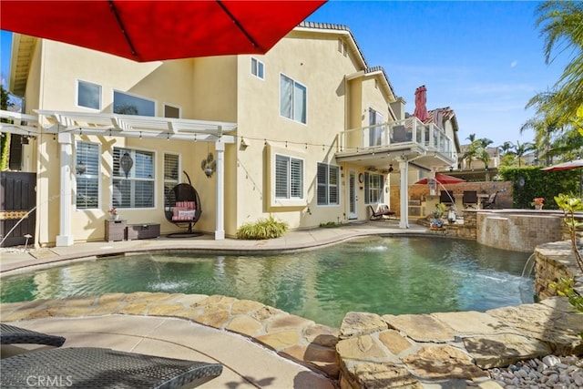 back of house featuring pool water feature, a patio area, a balcony, a pergola, and a pool with hot tub